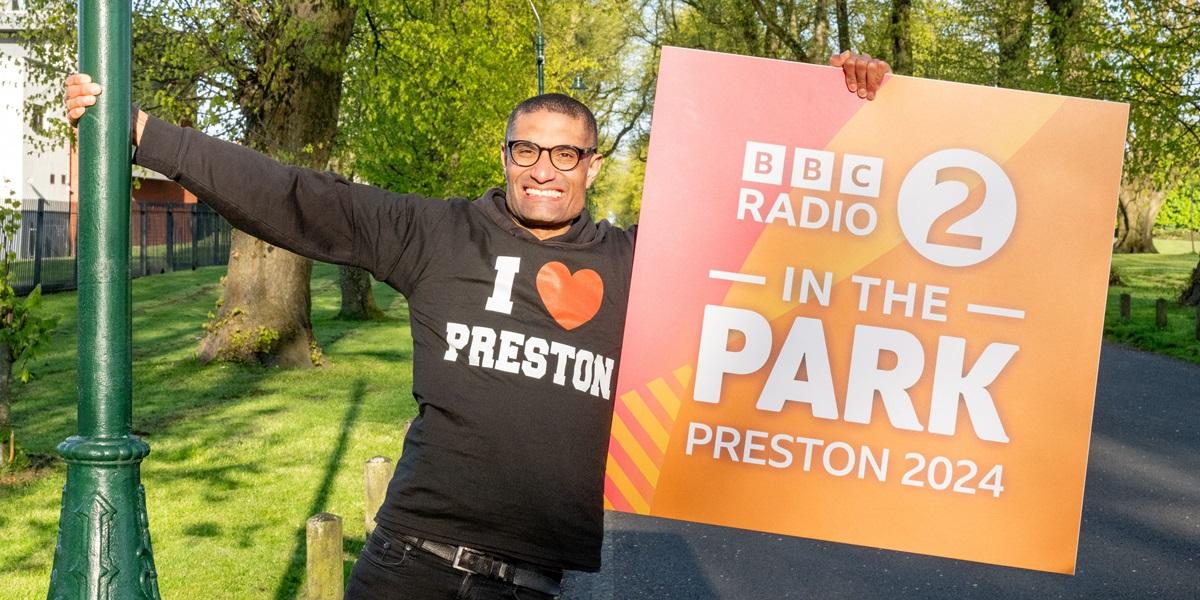 Richie Anderson holding up BBC Radio 2 in the Park banner at Moor Park