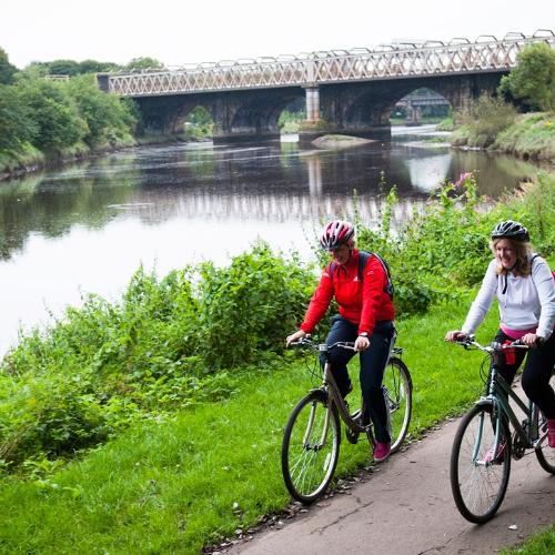 A group of cyclists on their bike alongside the Ribble in Preston